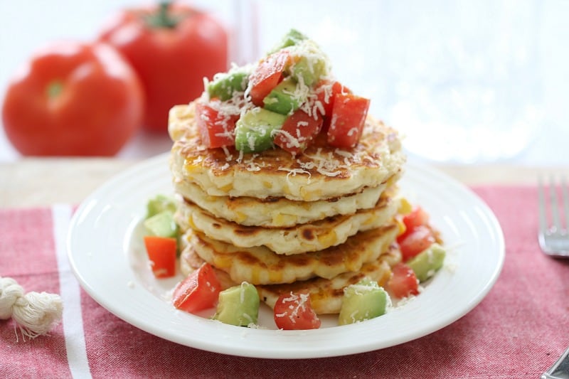 Cheesy corn fritters stacked with avocado and tomato salsa.